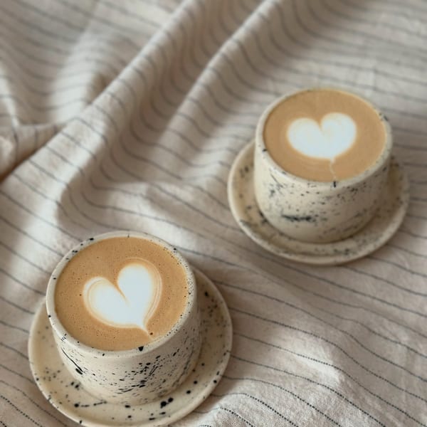 Dvě cappuccina s latte art v kropenatých šálcích s podšálky